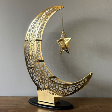 Shiny Gold crescent and star decor angled on a wooden sideboard, hanging star at right