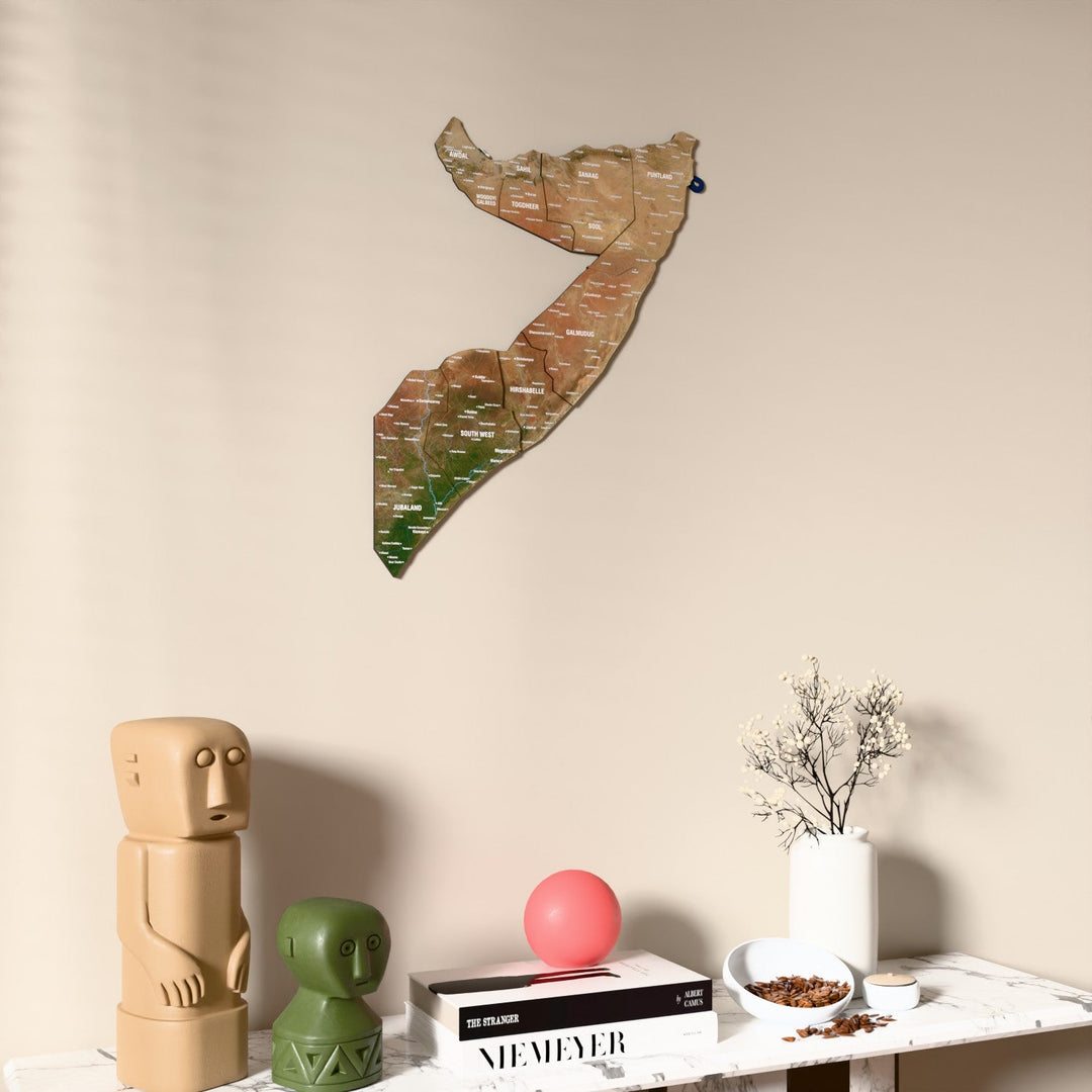 Satellite Somalia wooden wall map on a beige wall above a console with figurines