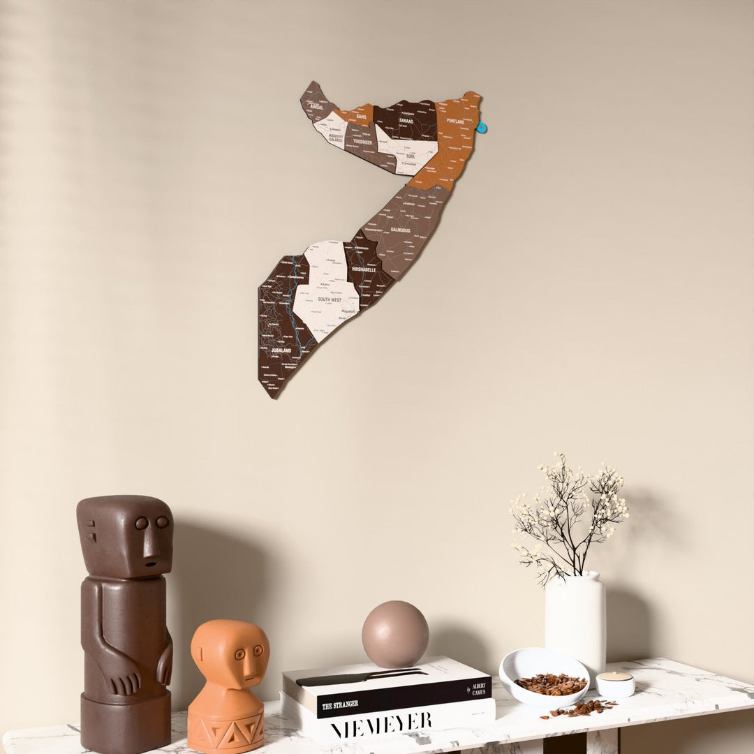 Soil Somalia wooden wall map on a beige wall above a console with figurines