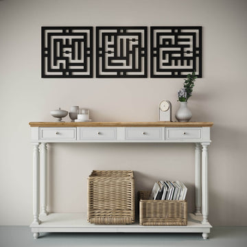 Black Kufic metal wall art set hung high above a white console with baskets, wide view