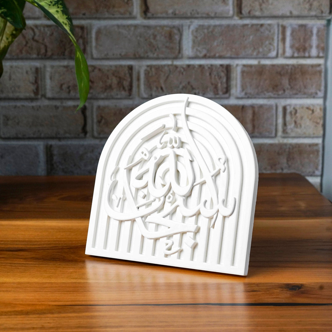 SubhanAllah stone relief arch plaque angled on a wooden table by a brick wall