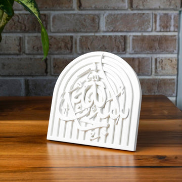 SubhanAllah stone relief arch plaque angled on a wooden table by a brick wall