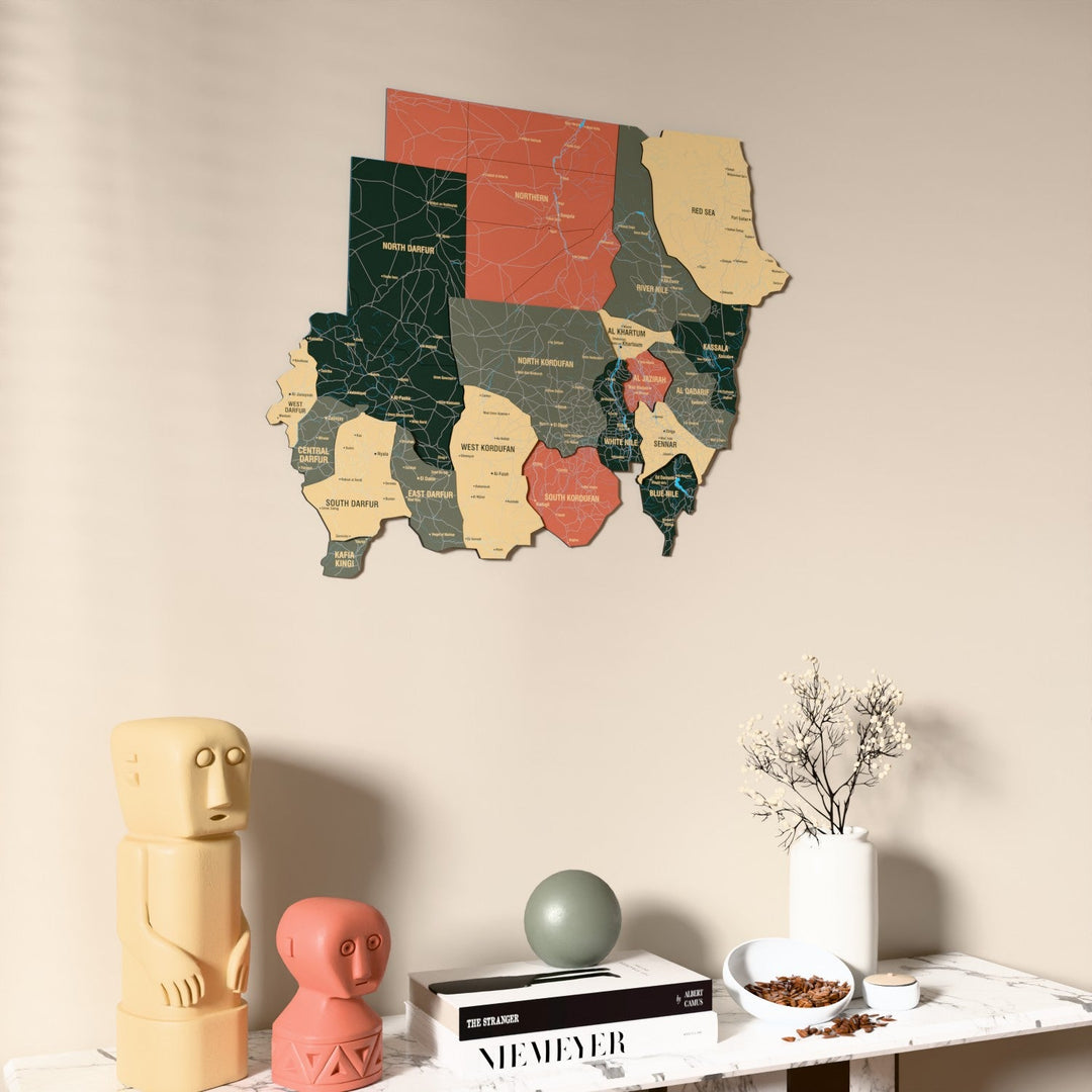 Sage Sudan wooden wall map on a beige wall above a console with figurines