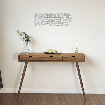 Silberne Metall-Wandkunst mit Sure Ad-Duha hoch an der Wand über einer Konsole mit Beinen, ganze Raumansicht