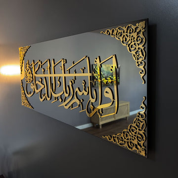Side view of Surah Al-Alaq tempered glass wall art with gold calligraphy on a dark wall