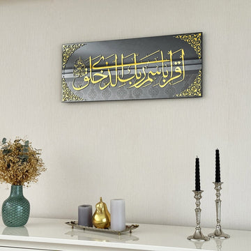 Surah Al-Alaq Ayat 1-2 glass wall art with gold Iqra calligraphy on a gray background above a white shelf