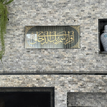 Surah Al-Alaq tempered glass wall art on a stone wall above a fireplace, front view