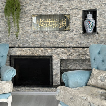 Wider view of Surah Al-Alaq tempered glass wall art above a fireplace with two blue armchairs