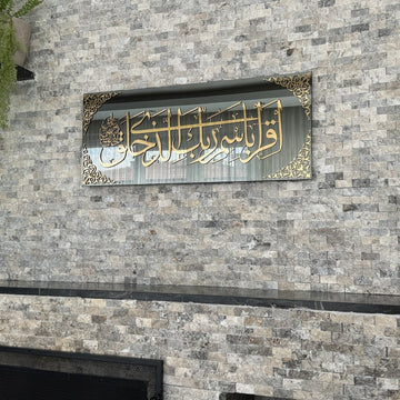 Surah Al-Alaq glass wall art on a stone wall, close crop of the gold Arabic calligraphy