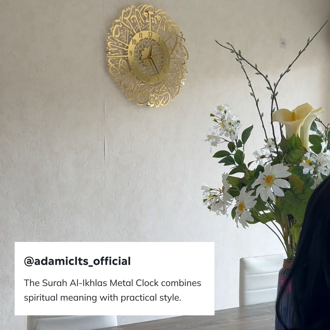 Gold Surah Al-Ikhlas metal clock on a white wall beside a vase of flowers with an influencer caption
