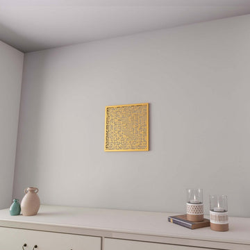 Gold Surah Fatiha square Kufic metal wall art on a white wall above a white dresser