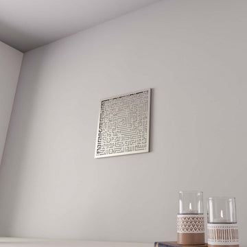 Silver Surah Fatiha square Kufic metal wall art on a gray wall with candle holders below