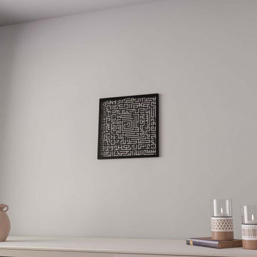 Black Surah Fatiha square Kufic metal wall art hung on a wall with candle holders below