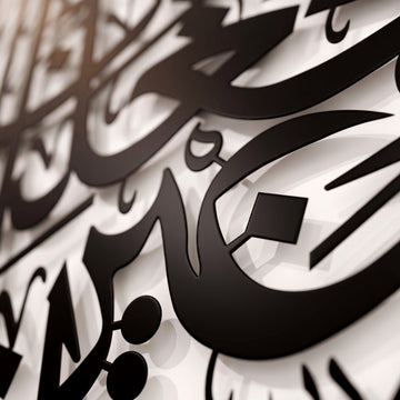 Nahaufnahme der schwarzen arabischen Metallbuchstaben aus Sure Al-Furqan, Vers 74, mit Schatten