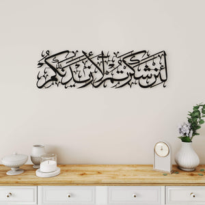 Black Surah Ibrahim verse 7 horizontal metal wall art on a cream wall above a white console