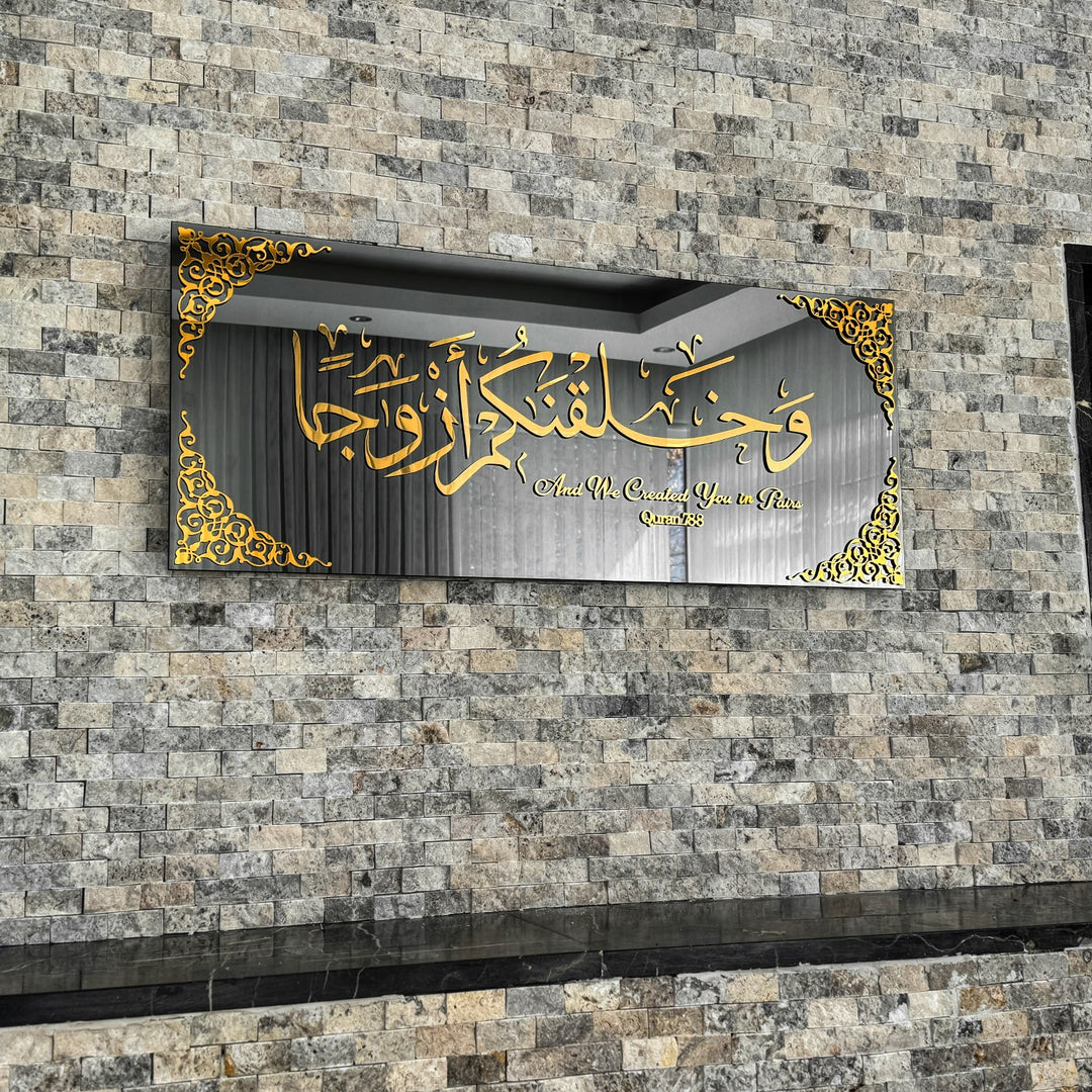 Gold Acrylic on Black Mirror Surah Naba Verse 8 tempered glass wall art, front view on a stone wall