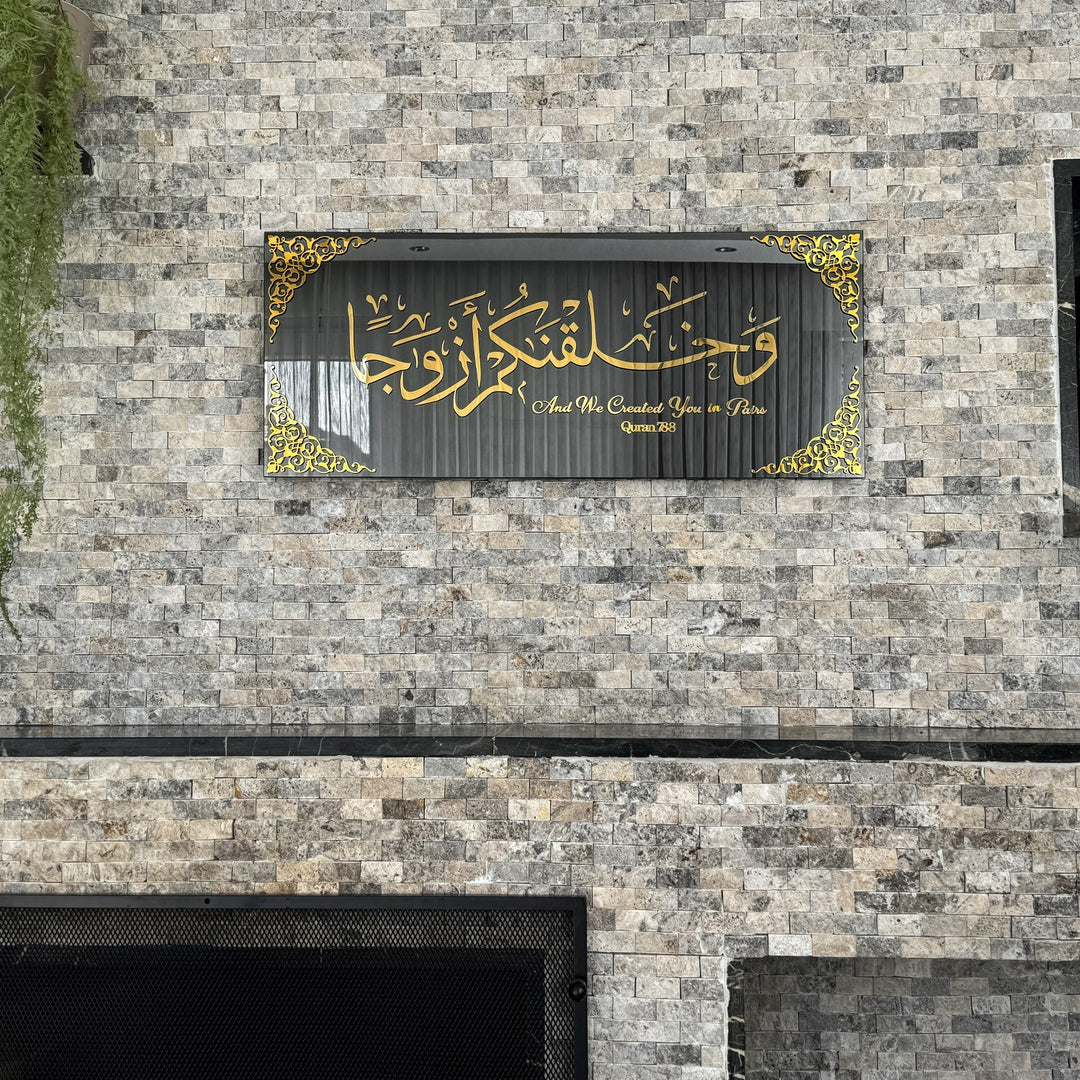Gold Acrylic on Black Mirror Surah Naba Verse 8 tempered glass wall art above a stone fireplace, wide view