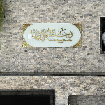 Gold Acrylic on Solid White Surah Naba Verse 8 tempered glass wall art, front view on a stone wall