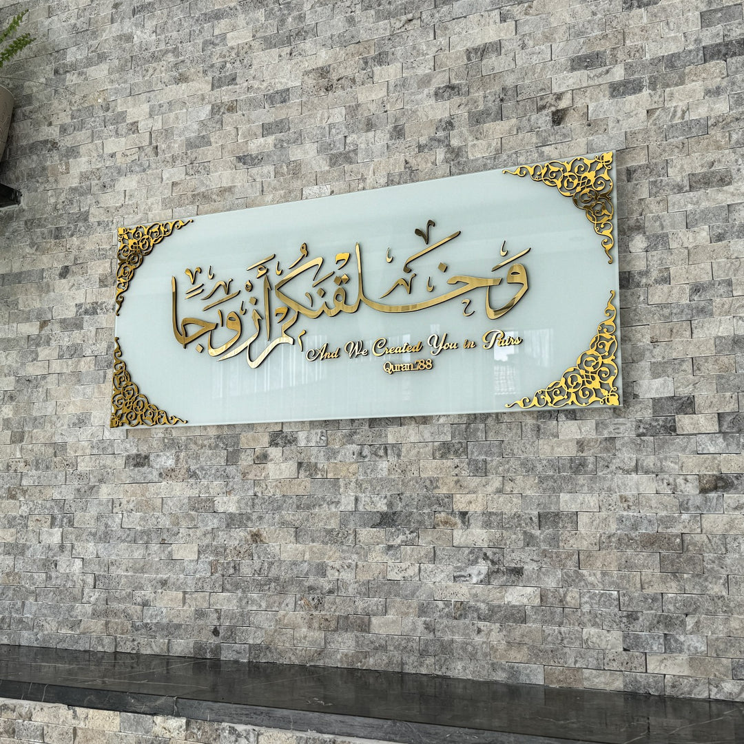 Gold Acrylic on Solid White Surah Naba Verse 8 tempered glass wall art hung on a stone wall