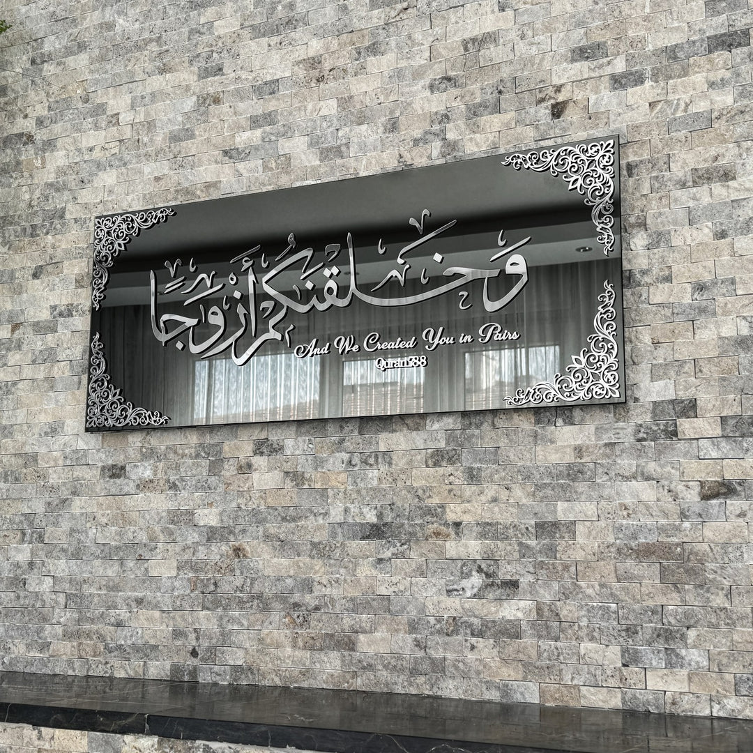 Silver Acrylic on Black Mirror Surah Naba Verse 8 tempered glass wall art hung on a stone wall