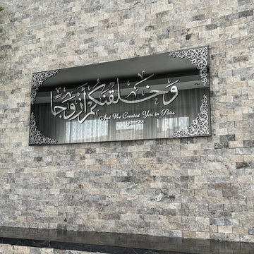 Silver Acrylic on Black Mirror Surah Naba Verse 8 tempered glass wall art hung on a stone wall