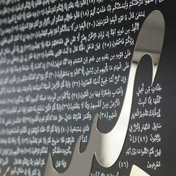 Close-up of the silver mirrored acrylic Ya-Sin lettering over the Arabic text of Surah Yaseen