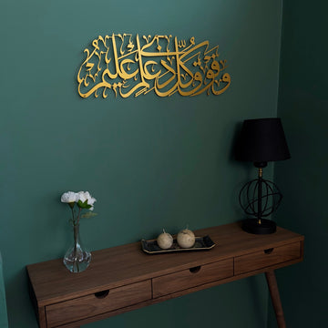Surah Yusuf Ayat 76 Matte Gold metal wall art on a dark green wall above a console table