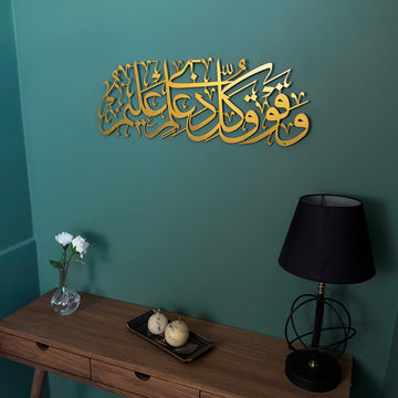Surah Yusuf Ayat 76 Matte Gold metal calligraphy on a green wall, angled view of the table
