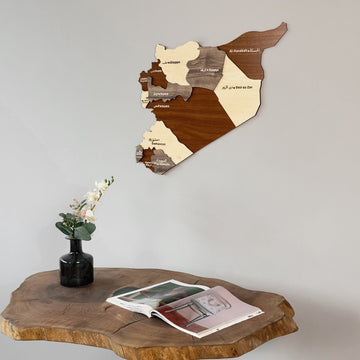 Syria wooden wall map at a side angle above a wooden table with flowers in a black vase