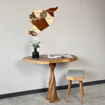 Wide view of the Syria wooden wall map on a gray wall beside a live-edge table and stool