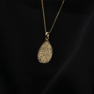 Ayatul-Kursi-Anhänger in Tropfenform in Gold, kleinere Ansicht an einer dunklen Kette vor Schwarz