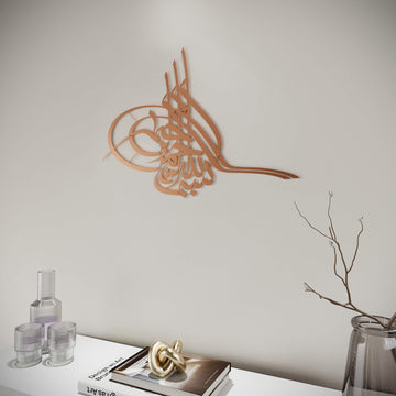 Metall-Wandkunst Tughra Bismillah in Kupfer, an einer hellen Wand, nähere Ansicht mit Zweigvase rechts