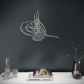 Metall-Wandkunst Tughra Bismillah in Silber, an einer dunklen Schieferwand über einer weißen Konsole