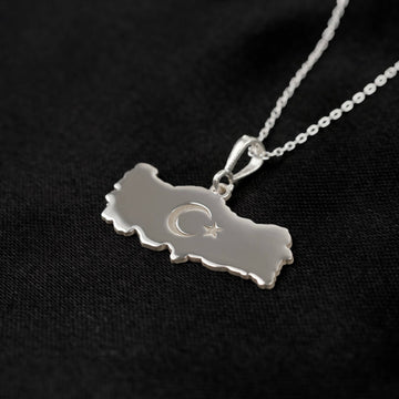 Close view of the Silver Turkiye map pendant, bail and chain on black fabric
