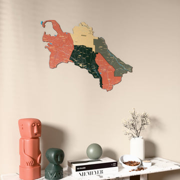Sage Turkmenistan wooden wall map on a beige wall above a console with figurines