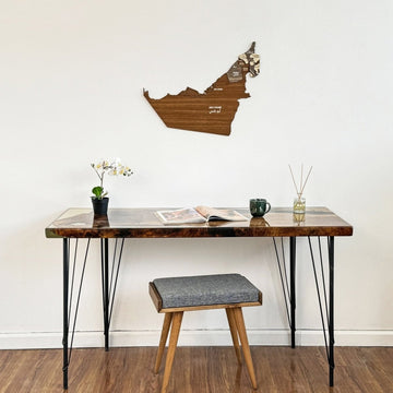 Wide view of the United Arab Emirates wooden wall map above a desk and a cushioned stool