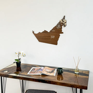 United Arab Emirates wooden wall map above a wooden desk with a flower and a mug