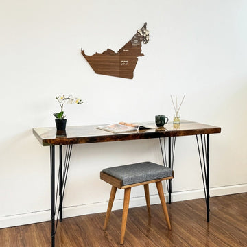United Arab Emirates wooden wall map on a white wall above a desk and stool, left of frame