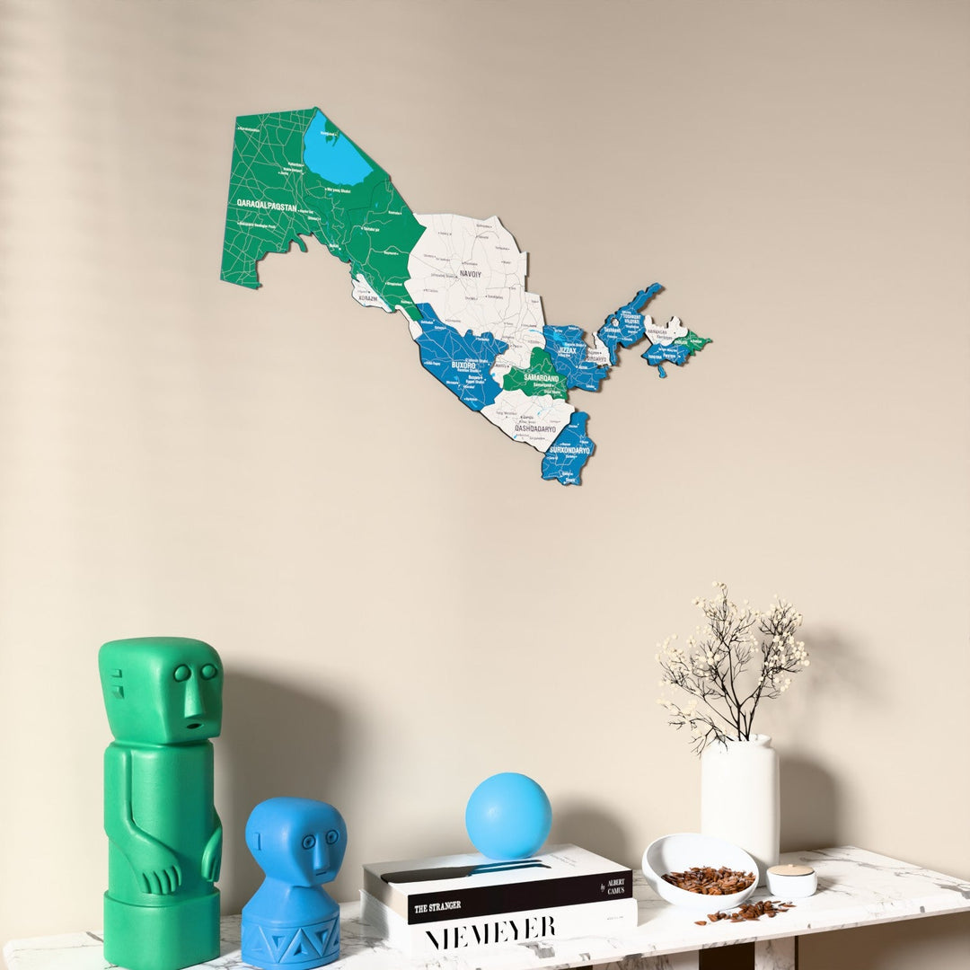 Flag colored Uzbekistan wooden wall map on a beige wall above a console with figurines