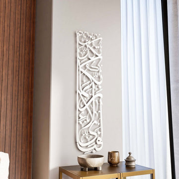 Vertikale Metall-Wandkunst Sure Rahman Vers 13 in Mattsilber neben einer holzvertäfelten Wand und einem Vorhang