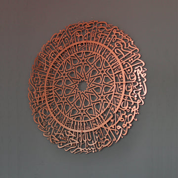 Kupferfarbene runde Metall-Wandkunst mit Sure Al-Fatihah an einer dunkelgrauen Wand, schräge Vorderansicht