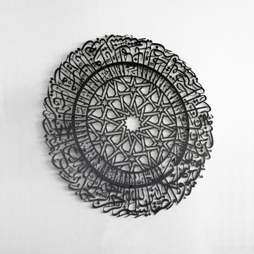 Schwarze runde Metall-Wandkunst mit Sure Al-Fatihah an einer weißen Wand, Ansicht von links