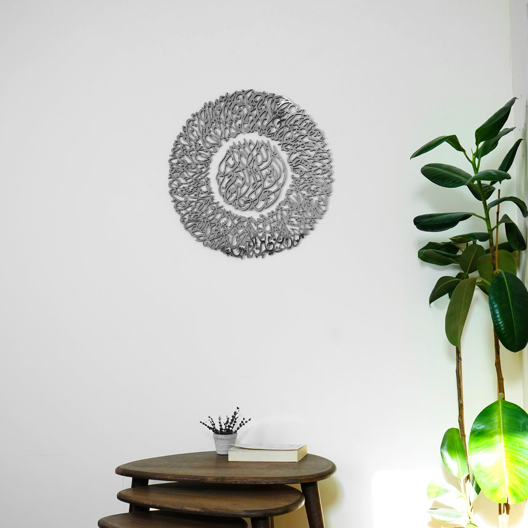 Full Silver Ayatul Kursi Diwani wall art above a wooden side table, next to a rubber plant
