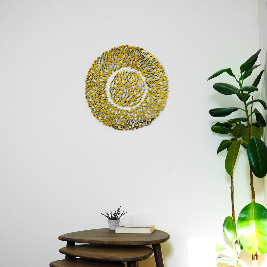 Full Gold Ayatul Kursi Diwani wall art above a wooden side table, next to a rubber plant