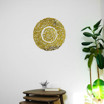 Full Gold Ayatul Kursi Diwani wall art above a wooden side table, next to a rubber plant