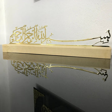 ديكور طاولة بخط البسملة من المعدن الذهبي اللامع على حامل خشبي بلون طبيعي (فاتح)، منظر أمامي