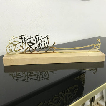 ديكور طاولة بخط البسملة من المعدن الذهبي اللامع على حامل خشبي بلون طبيعي (فاتح)، منظر بزاوية