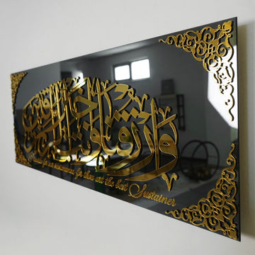 لوحة زجاجية بدعاء الرزق بأكريليك ذهبي من الجهة اليسرى مع انعكاس نافذة على الزجاج الأسود