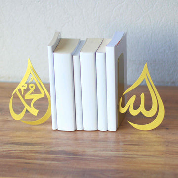 Goldene Buchstützen im Tropfendesign Allah und Mohammed (Friede sei mit ihm) halten eine Reihe weißer Bücher auf einem Holzregal