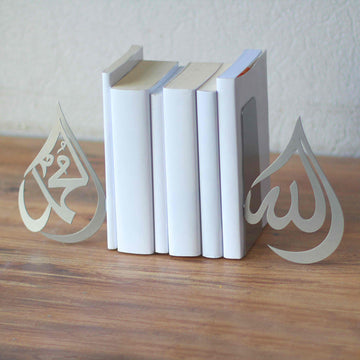 Silberne Buchstützen im Tropfendesign Allah und Mohammed (Friede sei mit ihm), nahe Ansicht mit weißen Büchern dazwischen